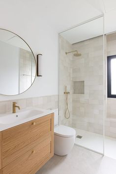 a bathroom with a sink, toilet and shower stall in the background is a large mirror