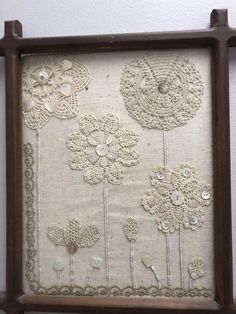 an old frame with some flowers and buttons on the front is hung up against a wall