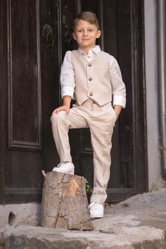 a little boy in a suit sitting on top of a tree stump next to a door