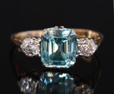 Vintage mid 1900's blue zircon and diamond gold ring set with a cushion cut natural blue zircon to the centre and two old cut natural diamonds (0.1 carat each) on the sides onto an 18k yellow gold band. The central zircon measures 6.9 by 6.2 weighing 1.78 karats. This attractive stone is in a vivid greenish blue colour with very good clarity. Diamonds: very bright and white with H/I color and VS clarity The shank is stamped 18 for 18k gold. Size: 5 (US), J1/2 (UK) finger size.  Please select the Blue Zircon Ring, Bridal Diamond Ring, Gold Gallery, Diamond Gold Ring, Sapphire Band, Engagement Ring Vintage, Diamond Ring Settings, Gold Ring Sets, Ring Ideas