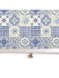 a blue and white tile design on the side of a wooden shelf with two handles