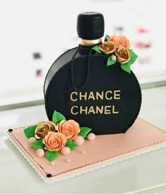 a black bottle with flowers on it sitting on top of a cake that says chance chanel