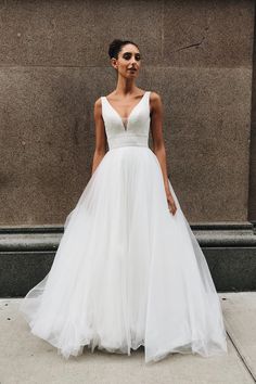 a woman in a white wedding dress standing on the sidewalk