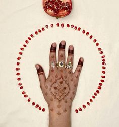 a woman's hand with henna tattoos and a pomegranate on it