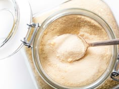 a glass jar filled with sugar sitting on top of a white counter next to a spoon