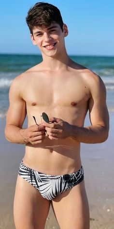 a shirtless young man standing on top of a beach