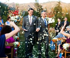 two men are walking down the aisle as confetti is thrown in the air