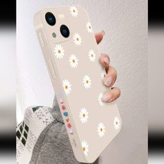 a woman holding up her phone case with daisies on it