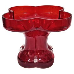 a red glass vase with four candles in it