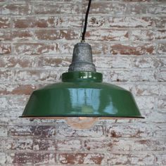 a green light hanging from a brick wall