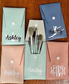 four personalized makeup brushes in their pouches on a wooden table with name tags