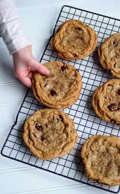 a person reaching for cookies on a cooling rack