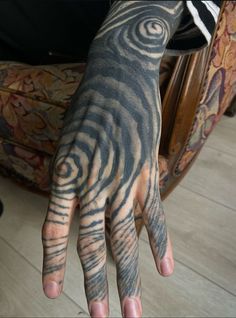 a person with black and white tattoos on their hands is holding his hand up to the camera