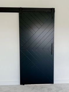 a black door in a room with white walls and carpeted flooring on the side