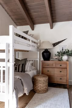 a white bunk bed sitting in a bedroom next to a wooden dresser and chest of drawers