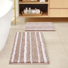 two bathroom rugs on the floor in front of a bathtub and sink area