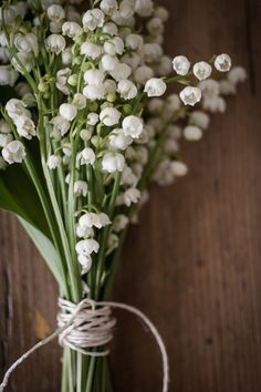 a bunch of white flowers sitting on top of a wooden table next to a string