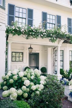 a white house with lots of flowers on the front