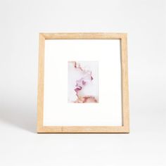 a white and pink flower in a wooden frame on a white background with space for text