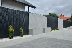 a black and white house with some plants in the front yard, on a cloudy day