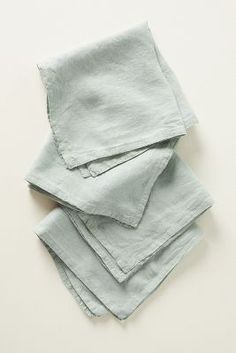 four folded napkins on top of each other in light blue linen, with one folded