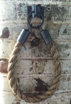 a rope hanging on the side of a brick wall with two metal hooks attached to it