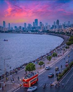 a view of the city from across the water at sunset with people walking and riding bikes