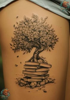 a woman's back with a tree on top of books and rocks around it