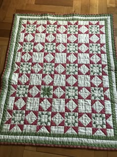 a red and green quilted table runner on a wooden floor with wood floors in the background