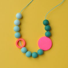 a necklace made out of plastic beads with a pink and blue disc hanging from it