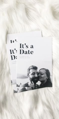 two magazine covers sitting on top of a white fur covered surface, with the title it's a date written in black