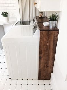 a white washer and dryer sitting next to each other in a room with black and white tile flooring