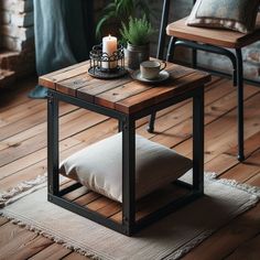 a wooden table sitting on top of a wooden floor next to a chair and pillow