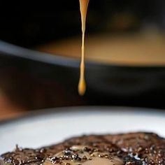 a piece of chocolate cake on a plate with syrup being poured over the top and sauce coming out of it