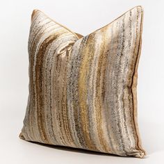 a gold and silver striped pillow on a white background