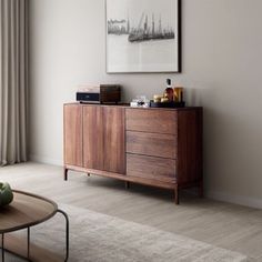 a living room with a large window and a wooden cabinet next to a coffee table