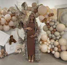 a pregnant woman standing in front of balloons and other decorations for her baby's first birthday