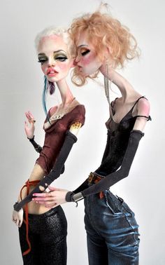 two women dressed in goth clothing and makeup posing for the camera with their hands on each other's hips