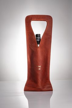 a leather bag with a bottle in it on a white surface, showing the inside