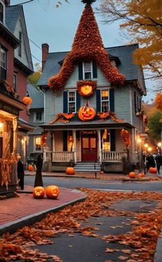 a house decorated for halloween with pumpkins on the ground and people walking in front