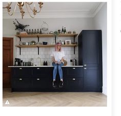 a woman sitting on top of a counter in a kitchen