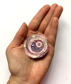 a person's hand holding a small button in the shape of a circle with buttons on it