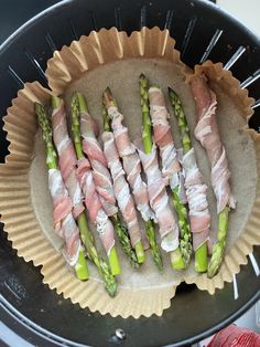 asparagus wrapped in prosciutto sitting on top of a paper plate