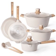 an assortment of white pots and pans with wooden handles