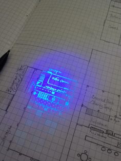 a blue light is on top of a drawing paper with a pen in front of it