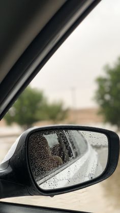 the rear view mirror of a car with rain on it