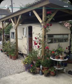 an old trailer is covered with flowers and potted plants