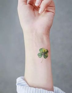 a small four leaf clover tattoo on the wrist