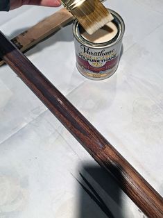 someone using a brush to paint a piece of wood