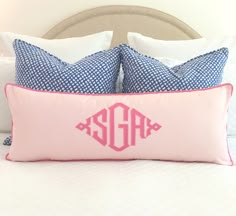 the monogrammed pillow on the bed is pink and has two matching blue pillows